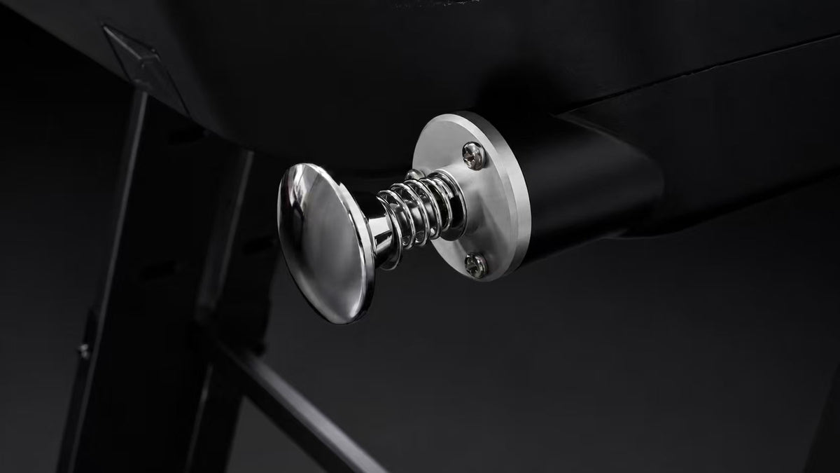 The chrome pinball plunger and its spring, mounted through the deck